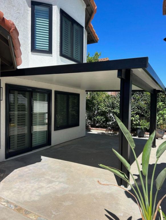 Dark bronze insulated aluminum patio cover with white ceiling panels attached to a stucco home